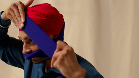 Primer-Plano-De-Estudio-De-Un-Hombre-Sikh-Atando-Tela-Para-Un-Turbante-Contra-Un-Fondo-Liso